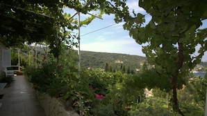 Un jardin agrémenté d’une pergola, d’un sentier et offrant une vue sur un paysage vallonné avec un plan d’eau.