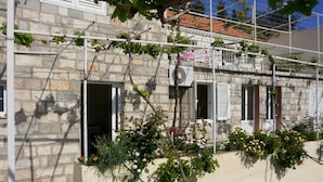 Un bâtiment en pierre doté de nombreuses portes et fenêtres ouvertes, dont certaines sont équipées de volets.