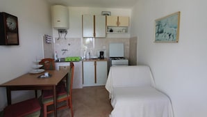 Une cuisine compacte comprenant une table à manger, des chaises, un lit et une horloge murale.
