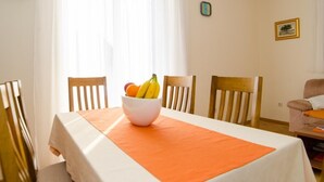 Un comedor con una mesa dispuesta para dos, un frutero y una silla.