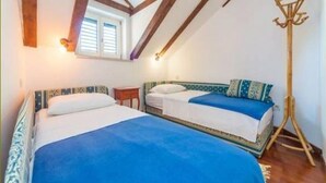 Ein Schlafzimmer mit zwei Betten, Holzbalken an der Decke, einem Fenster und einer Stehlampe.