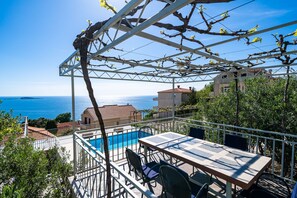 Eine Terrasse mit Pool, Sitzgelegenheiten im Freien und Meerblick.