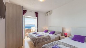 Ein Hotelzimmer mit zwei Betten, einem Fernseher, einer Klimaanlage und Meerblick.