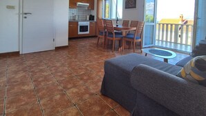Et kompakt køkken med spiseplads, sofa og en balkon med udsigt.