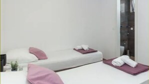 Een hotelkamer met twee bedden, elk met een kussen en een opgerolde handdoek.