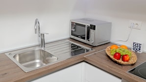 A modern kitchen with a stainless steel sink, a microwave, and a fruit basket on the counter. - Apartment City Gem - Studio (Dubrovnik)