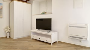 A room with a white wardrobe, a TV on a white stand, and an air conditioner on the wall. - Apartment City Gem - Studio (Dubrovnik)