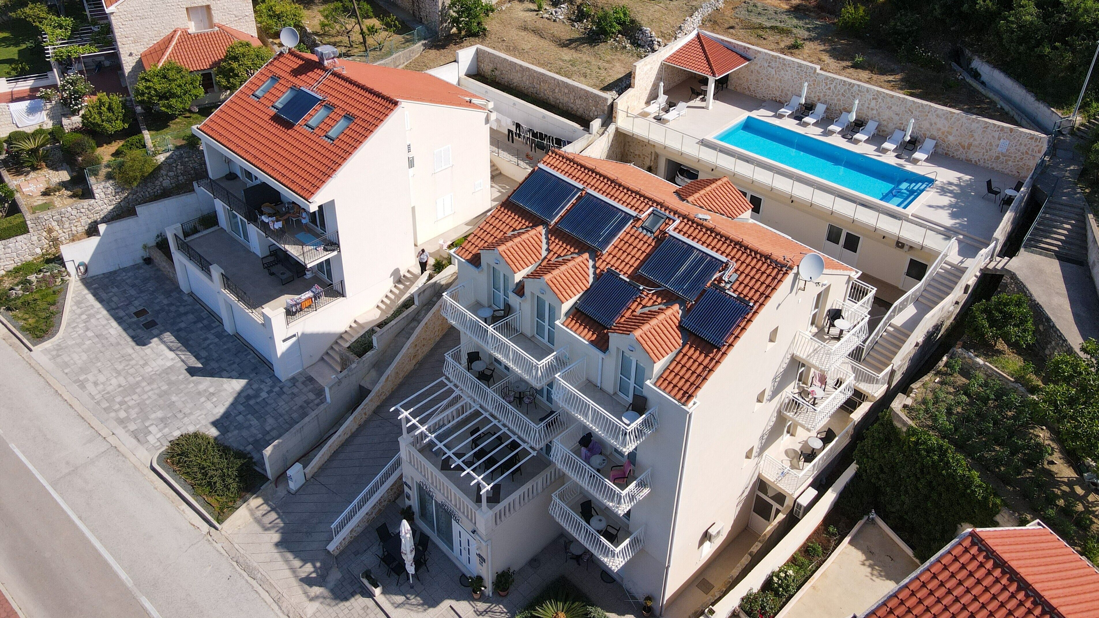 Un immeuble à plusieurs étages doté d’une piscine sur le toit, de panneaux solaires et d’espaces de détente en plein air.