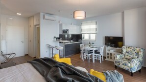 Un apartamento moderno con cocina, comedor y sala de estar con televisor y sillón floral.