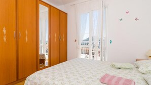 Un dormitorio con un armario de madera, una cama con ropa de cama floral y vistas a través de una ventana con cortinas.