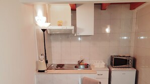 A compact kitchen with a dining table, chairs, a microwave, a small refrigerator, and a sink. - Apartments Minerva - One Bedroom Apartment No.1 (Dubrovnik)