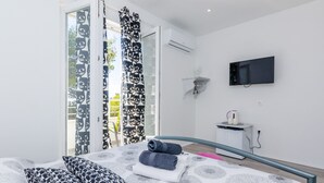 Une chambre à coucher moderne avec un lit, des coussins à motifs, un téléviseur à écran plat et une petite table de chevet.