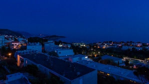Une ville côtière au crépuscule, avec des bâtiments et une vue sur la mer.