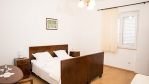 A bedroom with a wooden bed, a bedside table, a small round table, and a chair.