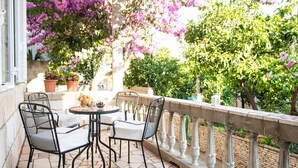 A patio with a round table and two chairs, a stone floor, and a railing.