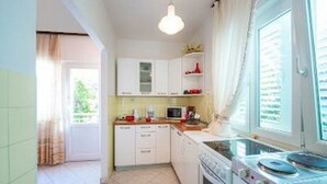 A compact kitchen with white cabinets, a microwave, and a stove. - Holiday Home Lido - Three Bedroom Holiday House with Terrace (Orebic)