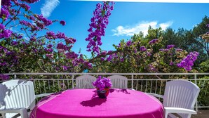 A round table with a pink tablecloth, surrounded by white chairs, set against a backdrop of purple flowers and a clear blue sky. - Holiday Home Lido - Three Bedroom Holiday House with Terrace (Orebic)