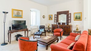 Ein Wohnzimmer mit Fernseher, einem roten Sofa, einem Holztisch und einem Kamin.