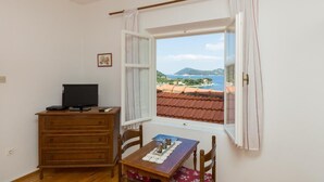 Una habitación con un aparador de madera, una mesa con bandeja y una ventana que ofrece vistas al paisaje costero.