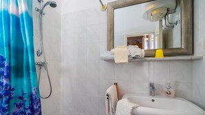 A bathroom with a shower, a sink, a mirror, and a towel rack.