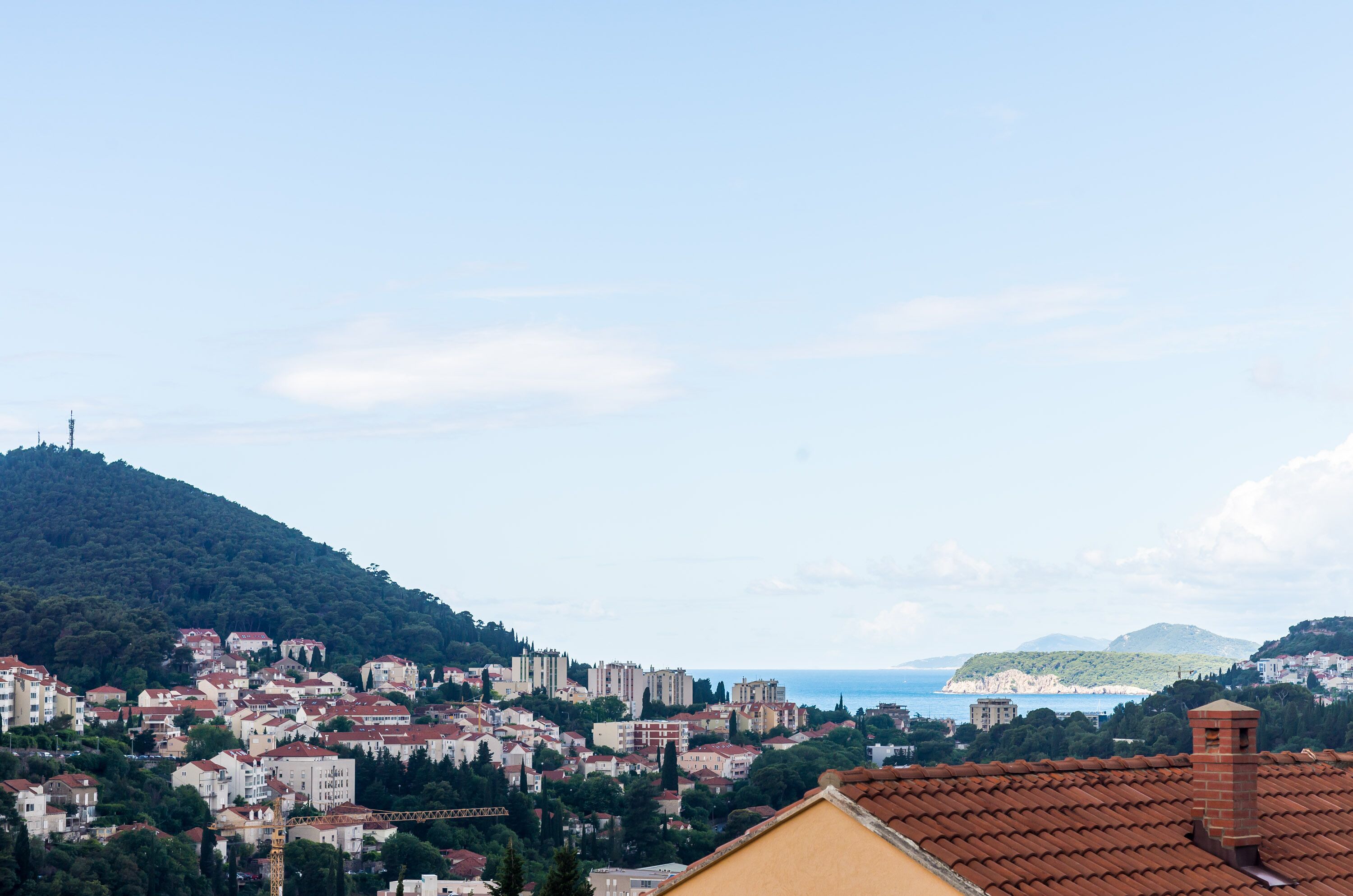 A coastal town with buildings, a hill, and the sea.