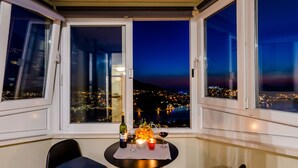 Ein Balkon mit Tisch für zwei Personen, ausgestattet mit einer Weinflasche, Gläsern und einer Kerze.