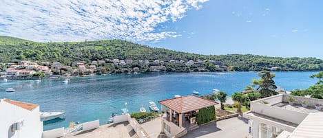 A coastal town with a marina, buildings with red roofs, and a clear blue sky.