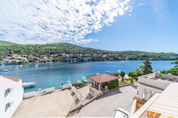 A coastal town with a marina, buildings with red roofs, and a clear blue sky.