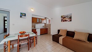 A compact living space with a dining table, chairs, a sofa, a kitchenette, and a small dining area.