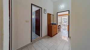 A hallway with a wooden cabinet, a mirror, and a door leading to a balcony.