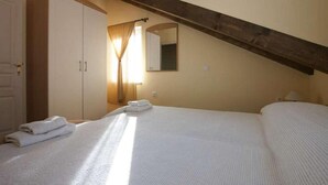 Een slaapkamer met een groot bed, een kledingkast, een spiegel en een schuine kap.