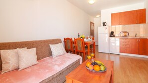 A living room with a sofa and a dining table with fruit. - Apartments Island Beat - Two Bedroom Apartment with Balcony and Sea View (A2) (ST) (Supetar)