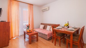 A cozy room with a wooden dining table set for two, a sofa, and a small table with fruit and drinks. - Apartments Island Beat - Two Bedroom Apartment with Balcony and Sea View (A2) (ST) (Supetar)