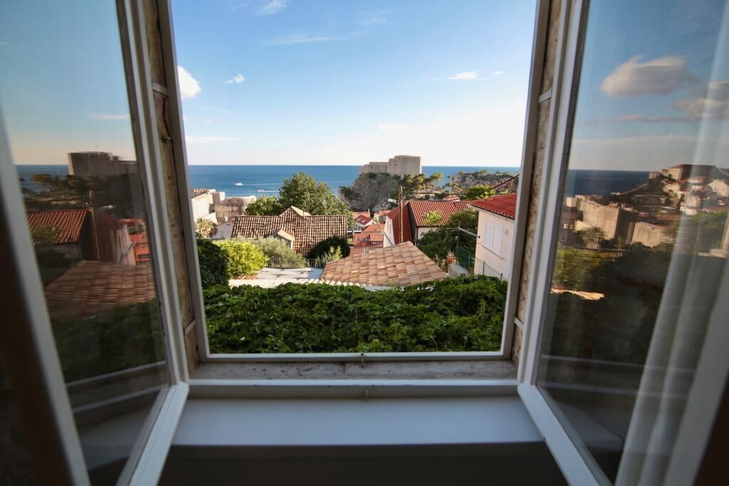 A view from a window overlooking a coastal town with historic buildings and a sea view.