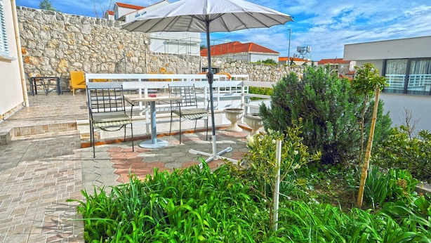 An outdoor patio with stone walls, a white fence, and a variety of seating arrangements including chairs and tables. - Villa Katarina - Double Room with Terrace (Ground Floor) (Dubrovnik)