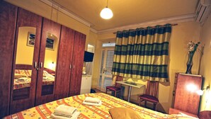 A hotel room with a bed, a desk, a chair, a wardrobe, and a curtain. - Villa Katarina - Double Room with Terrace (Ground Floor) (Dubrovnik)