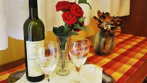 A bottle of wine, two wine glasses, and a vase with red roses on a checkered tablecloth. - Villa Katarina - Double Room with Terrace (Ground Floor) (Dubrovnik)
