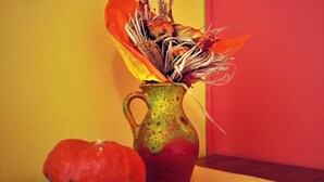 A vase with dried flowers and a pumpkin on a table against a yellow and red wall. - Villa Katarina - Double Room with Terrace (Ground Floor) (Dubrovnik)