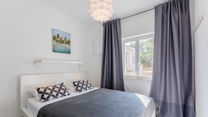 A bedroom with a bed, a painting, a window with curtains, and a ceiling light. - Villa Stella - Two Bedroom Apartment with Terrace and Sea View (Stella) (Splitska)