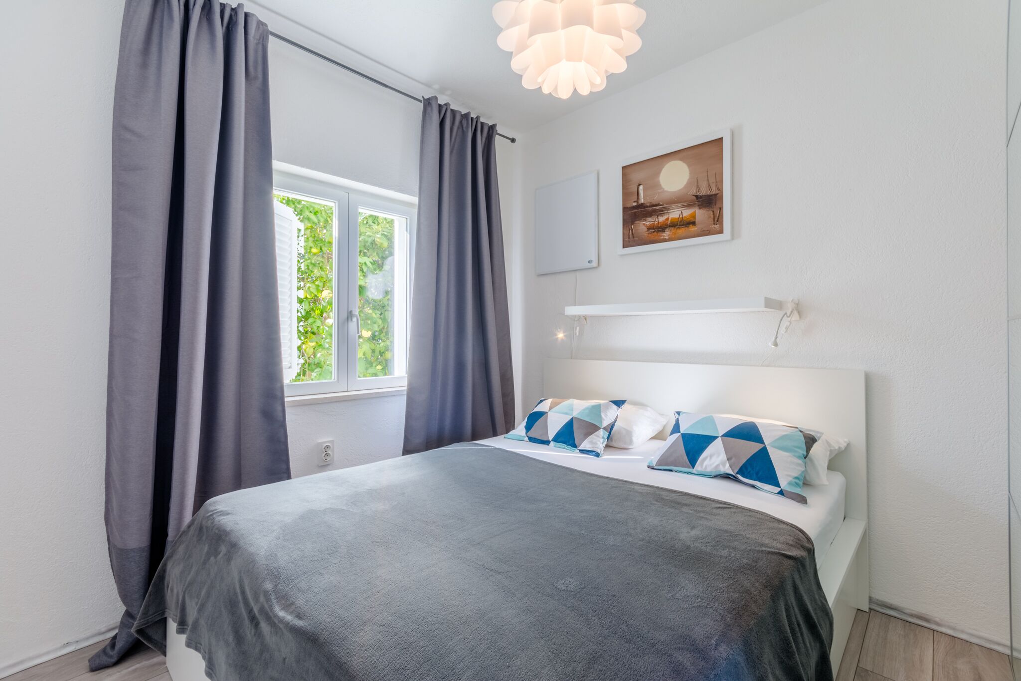 Ein Schlafzimmer mit Bett, Vorhängen, einem Gemälde und einem Fenster.