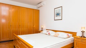 Une chambre à coucher avec un lit en bois, une armoire, une table de chevet avec une lampe et un tableau encadré au mur.