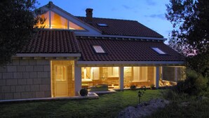 Ein modernes Haus mit Ziegeldach, einer Veranda und einem gepflegten Rasen.