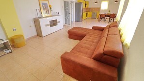 A modern living room with a large sectional sofa, a kitchen area with yellow cabinets, and a dining area with a table and chairs. - Apartments Villa Michele-Three Bedroom Apartment with Partial Sea View ( Grejp ) (Orebic)