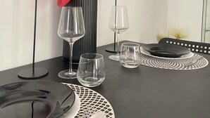 A dining table set with plates, cutlery, and glasses, accompanied by a vase with a red flower arrangement and two candle holders. - Apartments Mavi - Studio Apartment with Terrace and City View (Dubrovnik)