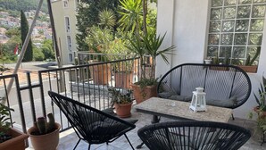 A balcony with two black chairs, a table, and potted plants. - Apartments Mavi - Studio Apartment with Terrace and City View (Dubrovnik)
