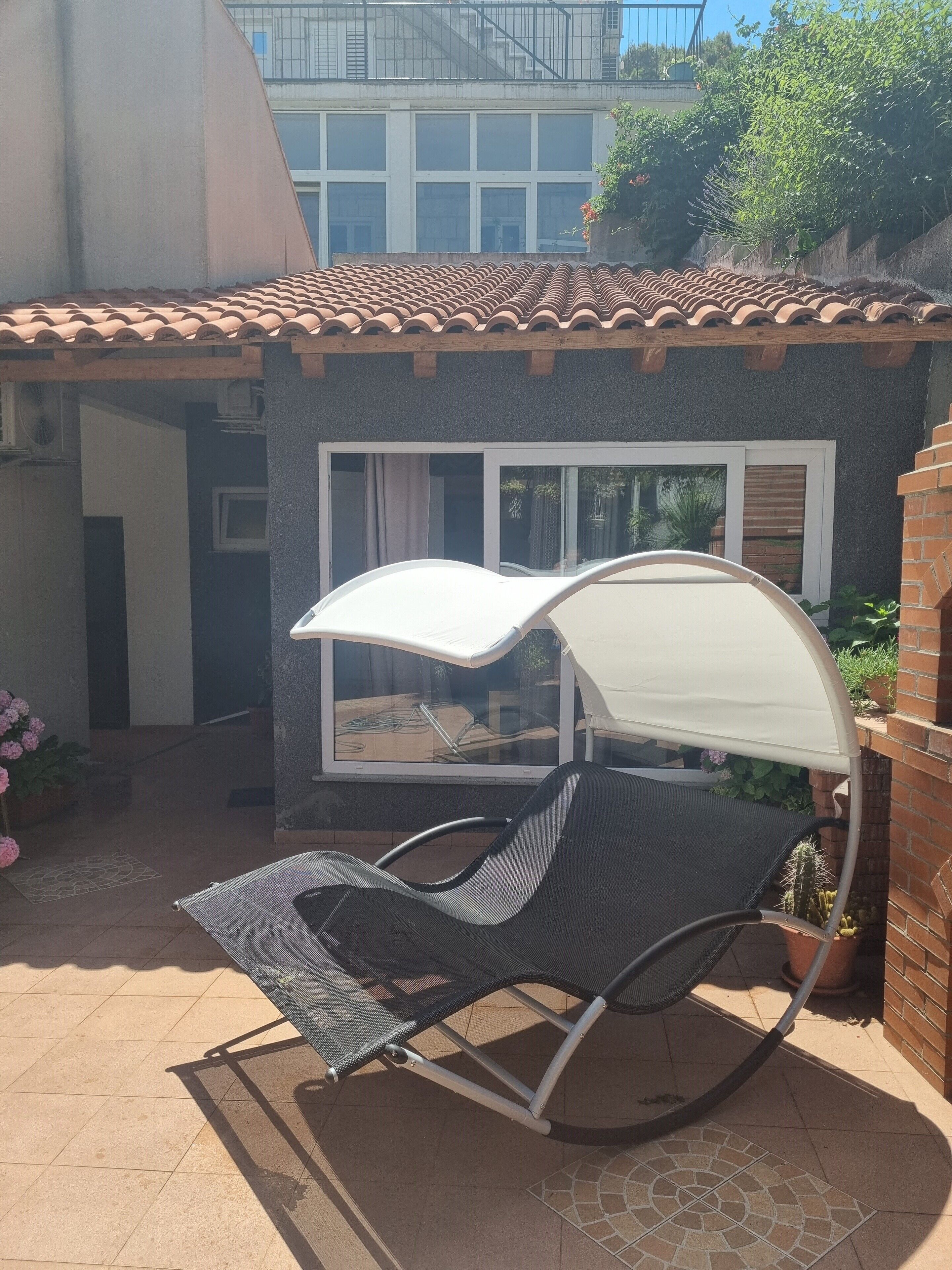 Un patio con una silla de descanso negra y un dosel blanco.