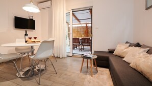 A modern living room with a sofa, a dining table with chairs, a TV mounted on the wall, and a sliding glass door leading to a balcony. - Apartment Boris (ST) - Two Bedroom Apartment with Terrace and Jacuzzi (Trogir)