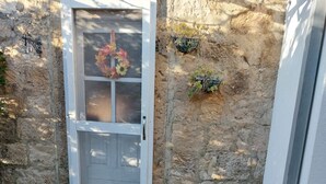 A stone wall entrance with a white door, a small step leading up to the door, and a brick ledge in front.