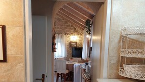 A narrow hallway leading to a dining area with a stone wall and a fireplace.