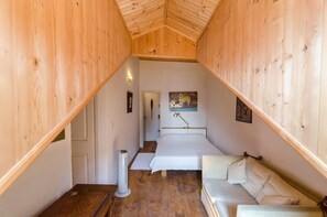 A cozy room with a wooden ceiling, a bed, a white sofa, and a painting on the wall. - Apartment & Room Dubrovnik Sweet Home - One Bedroom Apartment with Shared Terrace and City View (Dubrovnik)